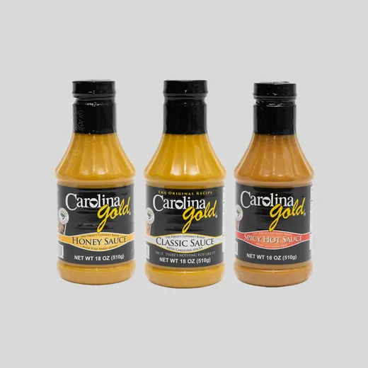 Three bottles of Carolina Gold BBQ sauce standing together against a neutral background.