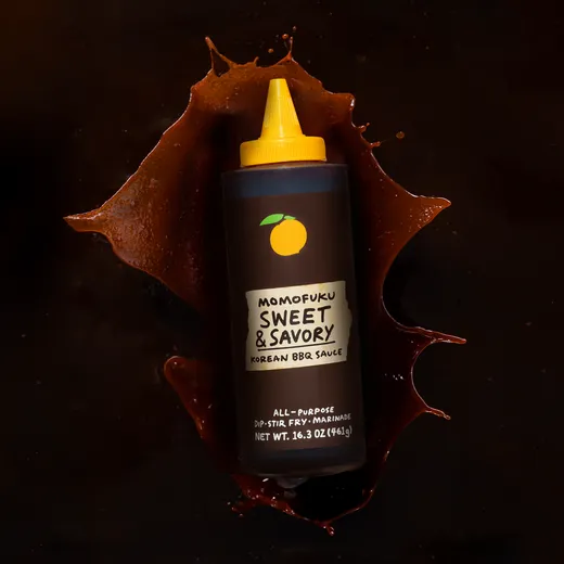 Momofuku BBQ sauce bottle with splashing sauce background.