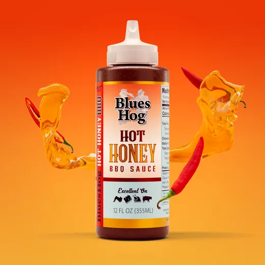 A front view of a single bottle of Blues Hog Hot Honey BBQ sauce against a solid orange backdrop.