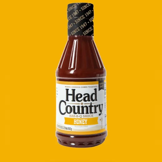 A full bottle of Head Country Honey BBQ sauce against a yellow background.