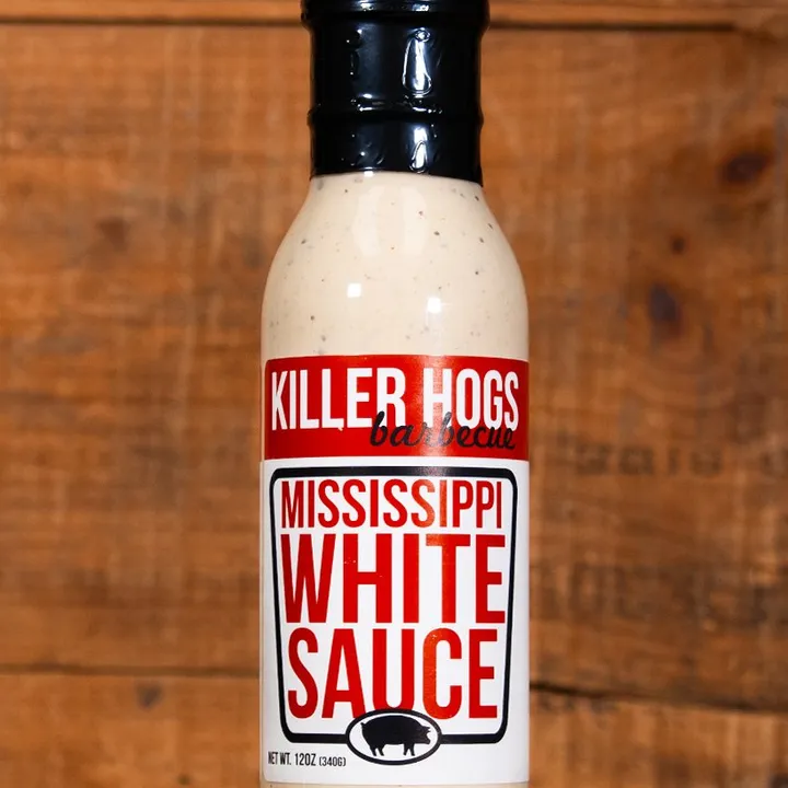 A single bottle of Killer Hogs Mississippi White Sauce against a wooden background.