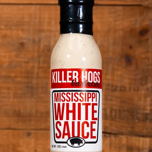 A single bottle of Killer Hogs Mississippi White Sauce against a wooden background.