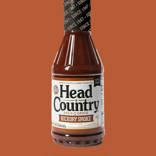 A full bottle of Head Country Hickory Smoke BBQ sauce against a plain background.