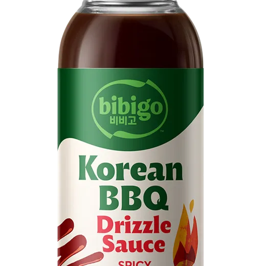 A bottle of Bibigo spicy Korean BBQ drizzle sauce against a black background.