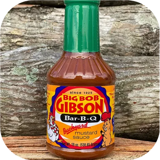 A single bottle of Backyard Mustard Sauce centered against a woody backdrop.