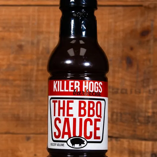 A single bottle of Killer Hogs BBQ sauce on a wooden surface.